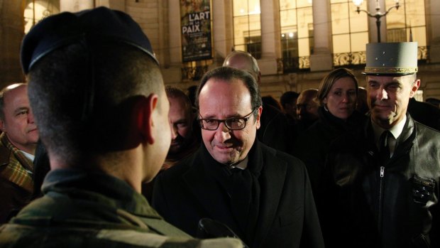 France's President Francois Hollande smiles at a French soldier as he visits the security measures at the Champs Elysees in Paris.