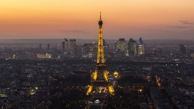 The Eiffel Tower stands illuminated on the skyline, a symbol of Parisians' pride in their city. 
