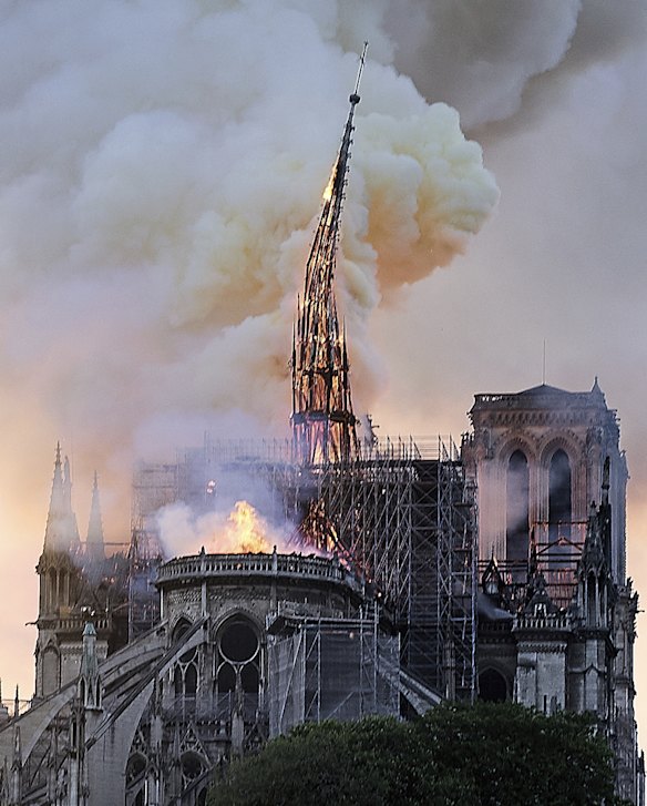 Flames and smoke rise as the spire on Notre Dame cathedral collapses in Paris, Monday, April 15, 2019. Massive plumes of yellow brown smoke is filling the air above Notre Dame Cathedral and ash is falling on tourists and others around the island that marks the center of Paris. (AP Photo/Diana Ayanna)