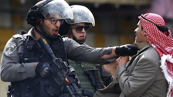 A Palestinian is pushed by Israeli policemen amid clashes in Hebron, in the occupied West Bank, after a Palestinian teenager stabbed two Israelis in Jerusalem before being shot dead by police.
