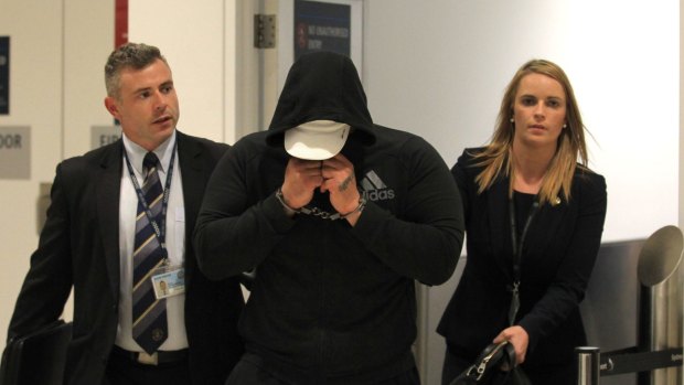 'Brownie' Ahmad, pictured with two detectives, was arrested after he stepped off a flight from Doha.