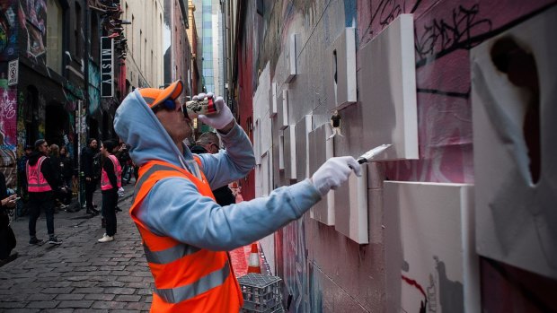 A "council worker" paints over art pieces by street artist Lush in Hosier Lane.