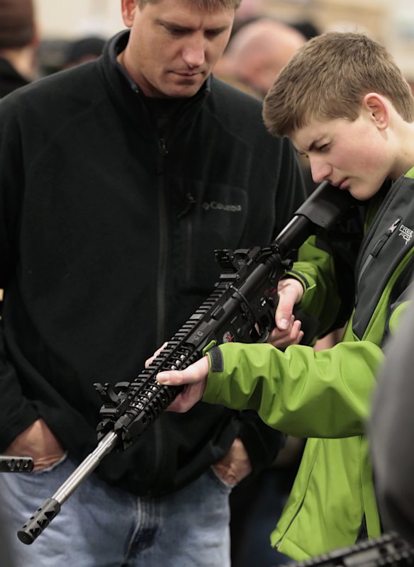 A boy holds a semi-automatic assault rifle as his father watches at the Rocky Mountain Gun Show in Sandy, Utah   January 2013. 