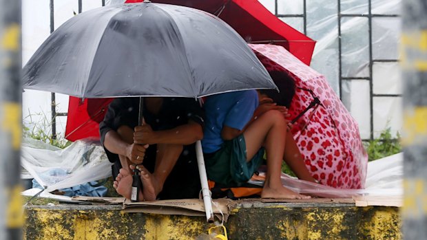 Residents huddle together under their umbrellas as strong winds and rain are brought by Typhoon Koppu.