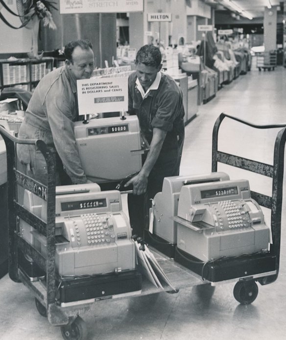 Workers lift converted machines on to store counters at Myer Department store, Bourke Street. 