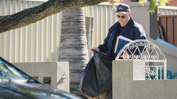 Police remove bags of evidence from a house in Punchbowl. 