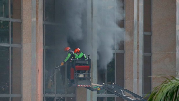Firemen break the glass panels to allow the smoke to escape from the Resorts World Manila complex.