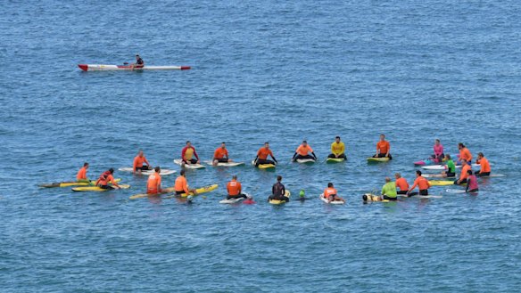 Friends paddled into the ocean off Tamarama Beach and threw sunflowers into the waves.