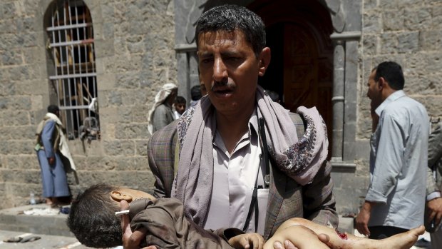 A man carries the body of a child out of the mosque which was attacked by a suicide bomber in Sanaa.