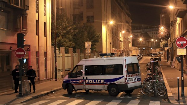 Police officers stand in a street next to Le Carillon, a bar-cafe where people were killed and several gravely injured. 