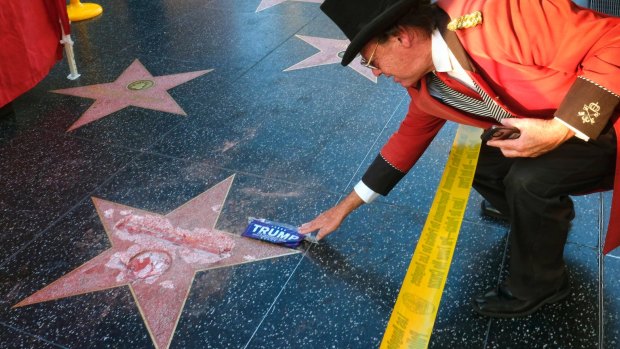 Gregg Donovan, who calls himself the unofficial ambassador of Hollywood, places a sticker for Donald Trump on Trump's vandalised star.