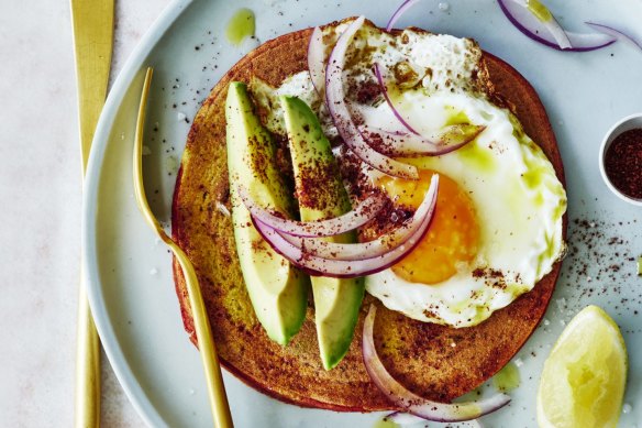 Chickpea pancakes topped with avocado, onion salad and a fried egg.