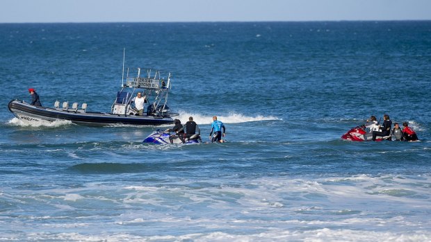 Mick Fanning (in blue) and Julian Wilson (red) are taken to the safety boat after Fanning was attacked by a shark during the final of the J-Bay Open on Sunday.
