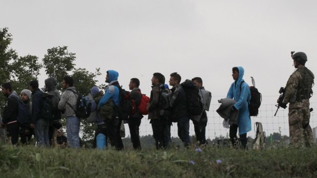A Hungarian soldier stands on guard as a group of migrants lines up to cross the border from Croatia in September, before Hungary closed its border.