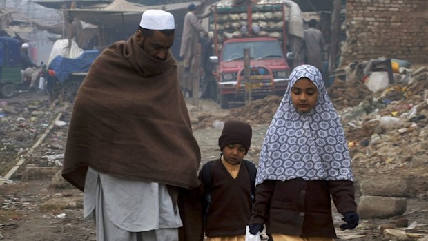 Cold comfort: A man walks his children home from school in the north-western city of Peshawar after the massacre. 