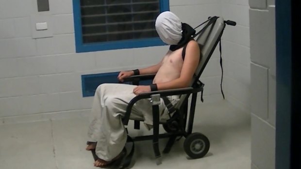 Dylan Voller is hooded an strapped into a restraining chair in the <i>Four Corners</i> footage.