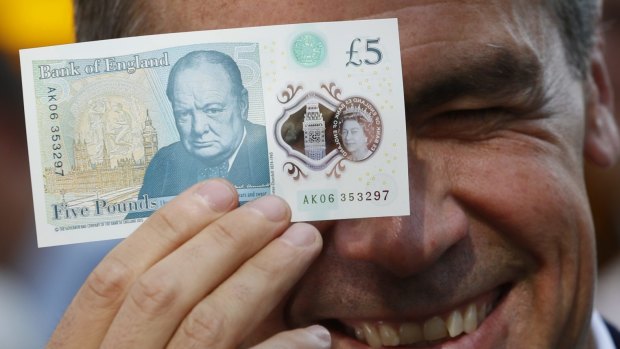 Bank of England governor Mark Carney poses with a new polymer five pound note.