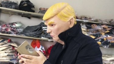 Reporter Sidney Leng tries on a Donald Trump mask for size.