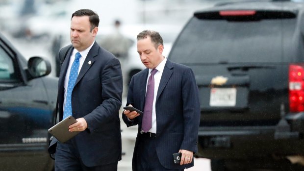 Former White House Chief of Staff Reince Priebus, with phone, walks in the rain.