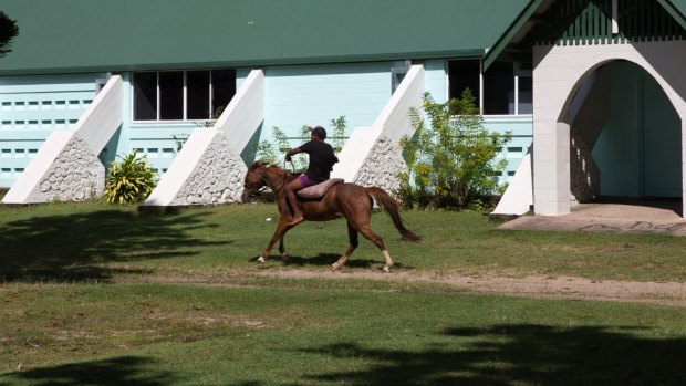 A boy rides one of the horses that roam freely around the Yarrabah community using a loose cushion for a saddle. 