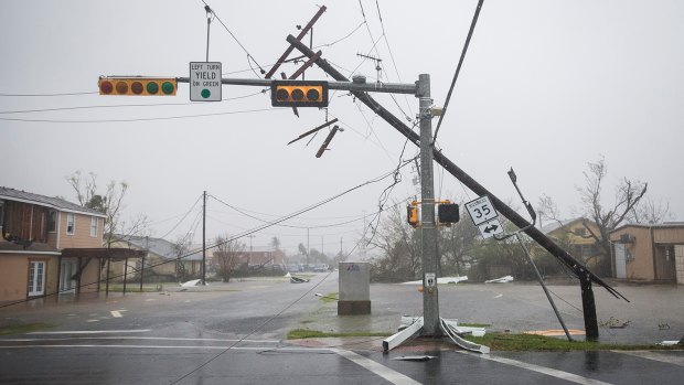 A snapped power pole leans against a stoplight after Hurricane Harvey ripped through Rockport.