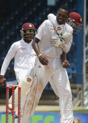 West Indies bowler Sulieman Benn is hugged by captain Denesh Ramdin, while celebrating the wicket of New Zealand's batsman Jimmy Neesham. 