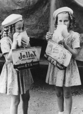 Two girls relish their fairy floss while carrying Jellex showbags at the 1946 Ekka.