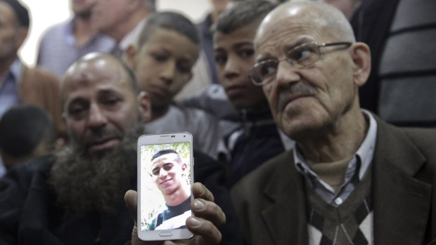 Mohammed, the father of Palestinian teenager Ali Abu Ghannam, who was shot dead by Israeli police officers, shows his son's photo on a mobile phone in Jerusalem.