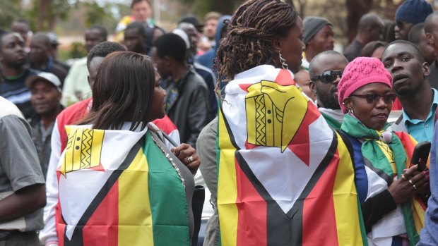 Protesters draped in Zimbabwean flags stand outside Harare Magistrates Court in Harare, in July.