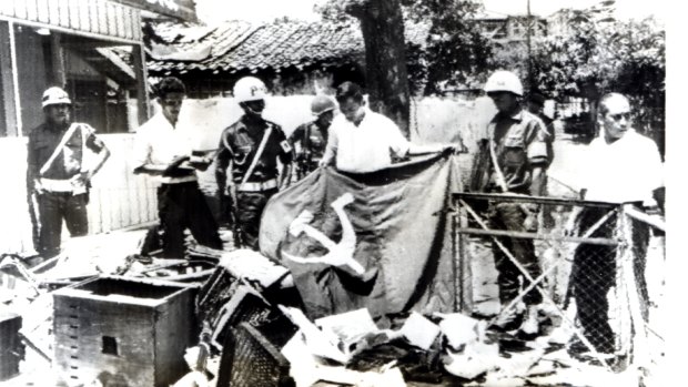 Indonesian police and a youth hold a Communist flag in the ruins of Indonesian Communist Party headquarters in Jakarta after it was ransacked by anti-communist demonstrators in 1965.