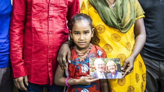 Divya, 8, holds a photo of Dick and Pip Smith.