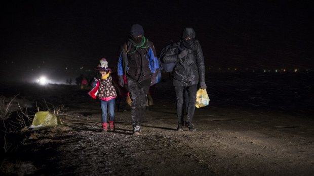 A family of refugees walks through the night to reach the Macedonia-Serbia border. 