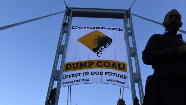 Two activists unveil a banner protesting coal financing by the Commonwealth Bank in Sydney, Friday, May 5, 2017. 