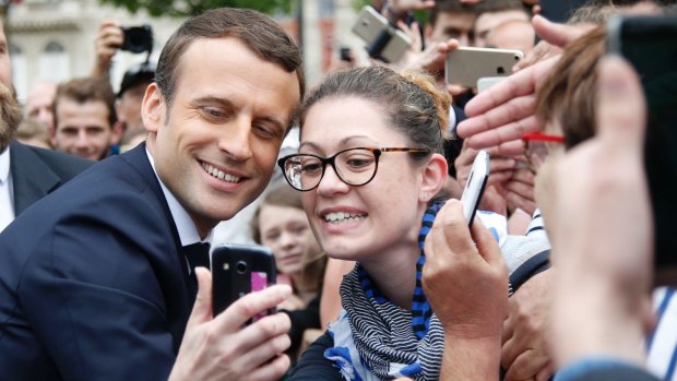 Emmanuel Macron, left, poses for a selfie after a ceremony at the Arc de Triomphe.