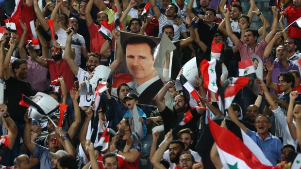 A fan holds a portrait of Syrian president Bashar al-Assad as supporters celebrate a goal against Iran last month.