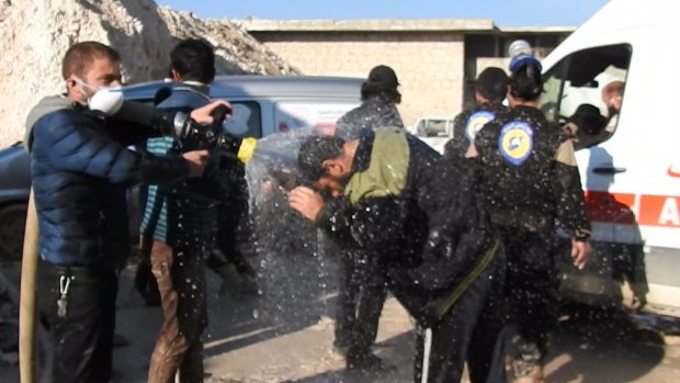 Civil defence workers spray water on victims after the chemical weapons attack near Idlib. 