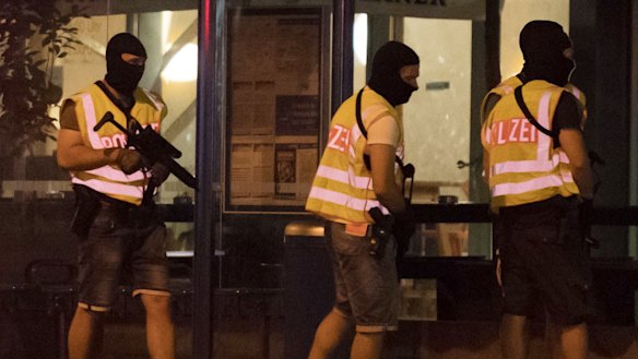 Masked police stand at a bus stop in front of the Olympia mall where a shooting took place in Munich.