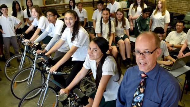 Casula High School science teacher Ken Silburn with students on bikes that produce electricity to power different lights, teaching them about energy use and power consumption.