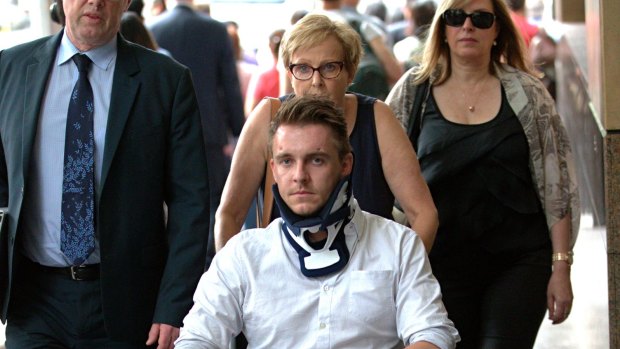 Tom Adamson arrives at court in a wheelchair and neck brace.