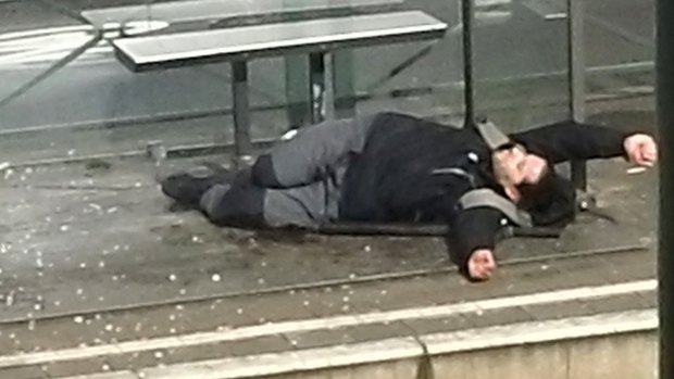 An injured man lays on the ground at a tram stop in Brussels, Belgium, on Friday.