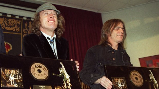 Malcolm Young (right) and fellow AC/DC founder and brother Angus Young pose with a presentation for their album Stiff Upper Lip in Spain in 2000.