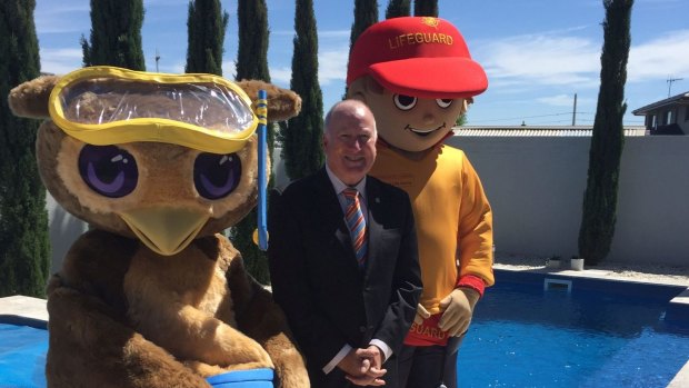 ACT Minister for Planning and Land Management Mick Gentleman with mascots from the Royal Life Saving Society and Kids Alive promote a new campaign to raise pool safety awareness.