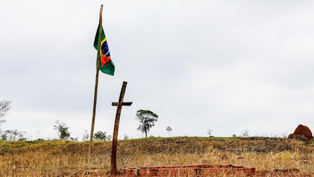 A bloodied flag, a cross and a brick grave mark the place where Clodiode dos Santos, 26, was killed.