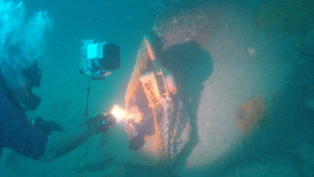 Shinatria Adhityatama, from the National Research Centre of Archeology Indonesia, inspects a chain hoist at the shipwreck site. The hoist is evidence of salvage activities. 