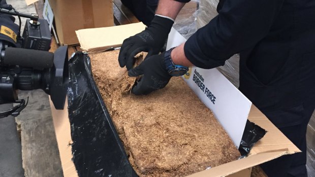 Customs officers sort through some of the 71-tonnes of illicit tobacco they seized in June, 2015  