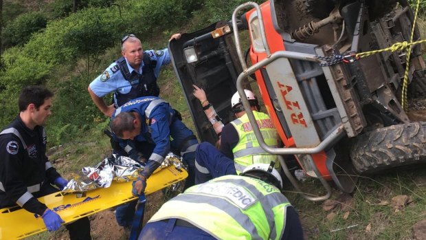 Emergency services help the woman as she remains trapped in the overturned RTV.