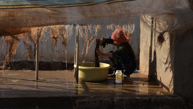  A girl washes clothes inside Khazer camp.