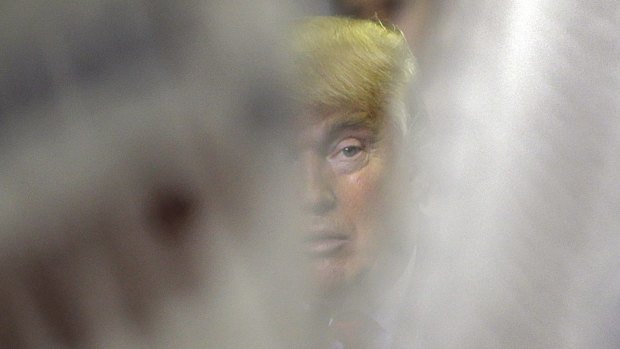 Republican presidential candidate Donald Trump is seen through campaign signs during a rally on Friday.