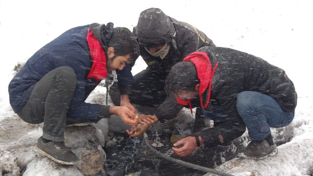 At a camp in Serbia, refugees wash their hands outside in the snow.