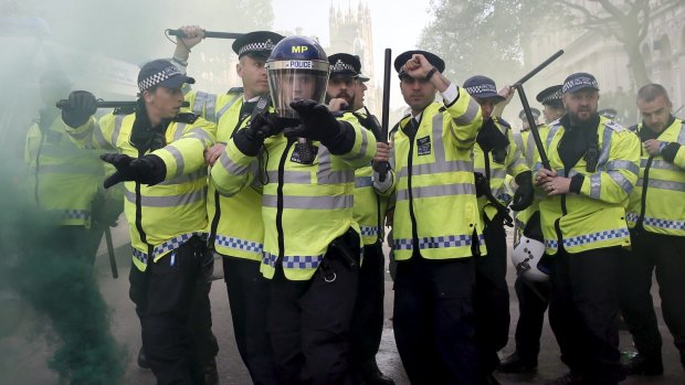 Police raise their batons amid smoke from a smoke bomb at the gates of Downing Street. 